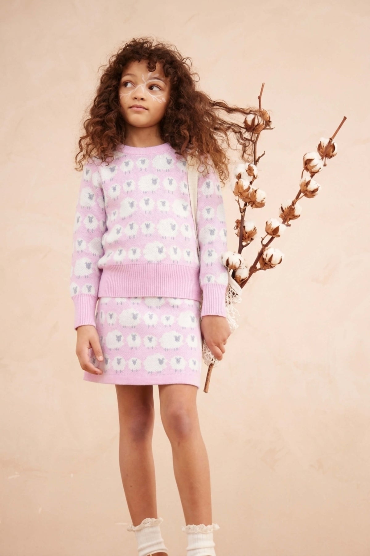 Girl wearing the Little Bo Peep jumper and skirt set in bubble gum pink