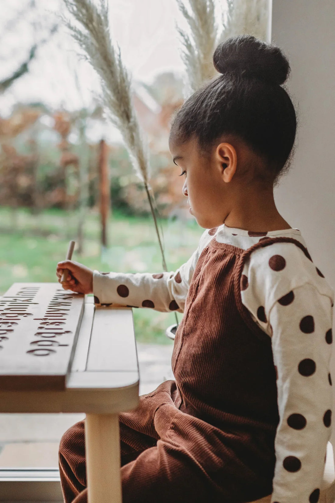 Girl practising writing with wooden Montessori letter board - unlocking your child's potential with the Montessori method UK | Kiddykind