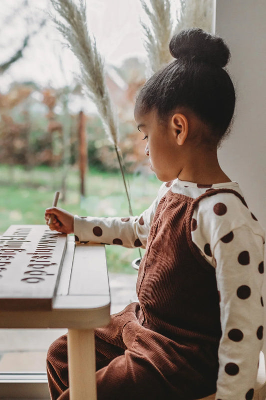 Girl practising writing with wooden Montessori letter board - unlocking your child's potential with the Montessori method UK | Kiddykind
