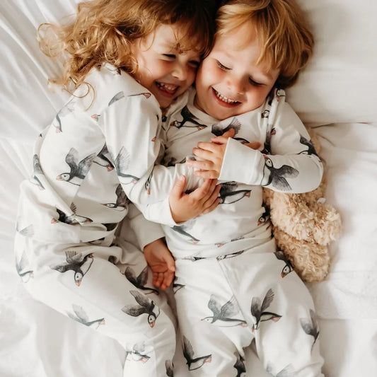 Two children laughing together in matching organic cotton pyjamas - best plastic-free baby and kids gift ideas UK | Kiddykind