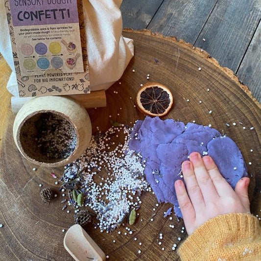 Child playing with colourful natural playdough on wooden table - non-toxic natural playdough versus plastic alternatives UK | Kiddykind
