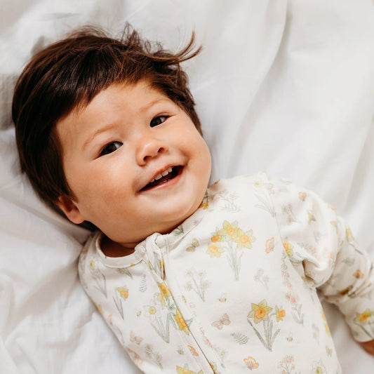 Image of baby smiling wearing organic cotton and bamboo babygrow, super soft sleepwear for an article discussing non-toxic kids skincare