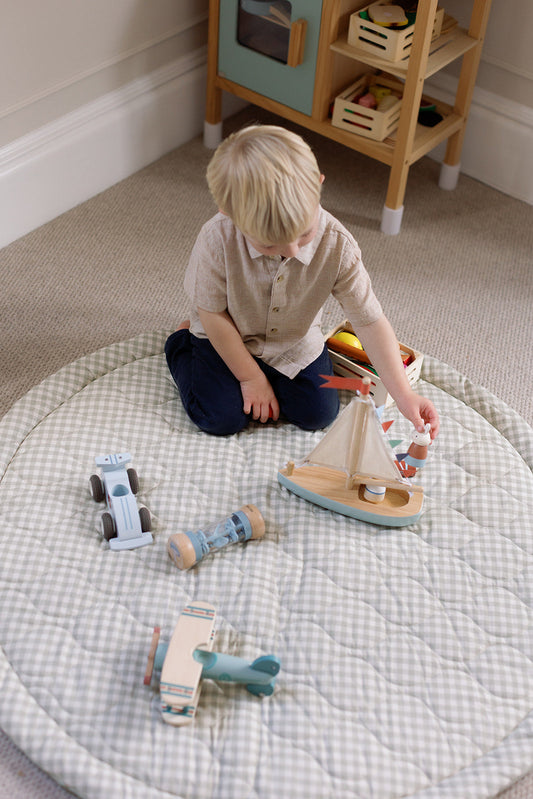 Child sitting on a nursery playmat surrounded by wooden toys - best wooden toys UK 2026 sustainable educational play | Kiddykind