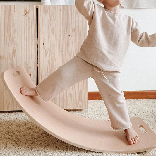 Toddler balancing barefoot on a Curve Lab wooden balance board at home, a birthday present made for keeping.