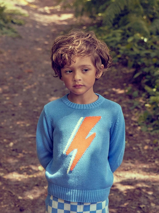 Boy in organic cotton jumper walking along a sunlit forest path - complete guide to buying sustainable baby and kids clothing UK | Kiddykind