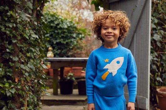 Child in natural merino wool rocket jumper playing outdoors in autumn - wool and cashmere versus polyester for kids UK | Kiddykind