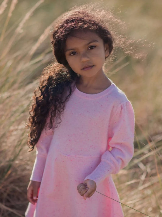 Girl in organic cotton cashmere dress standing in a wildflower meadow - organic versus conventional cotton what parents need to know UK | Kiddykind