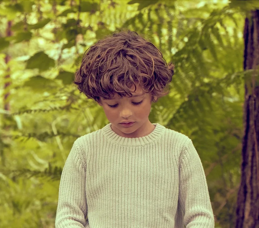 Child wearing grey waffle organic cashmere jumper playing outdoors in nature