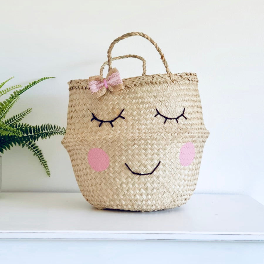 Handwoven seagrass storage basket with smiling face and bow