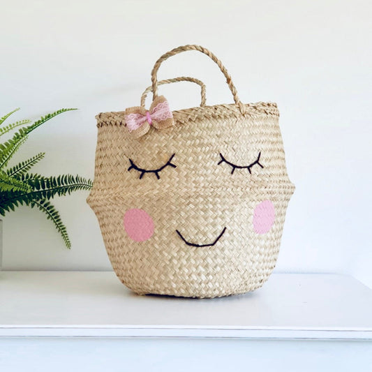 Handwoven seagrass storage basket with smiling face and bow