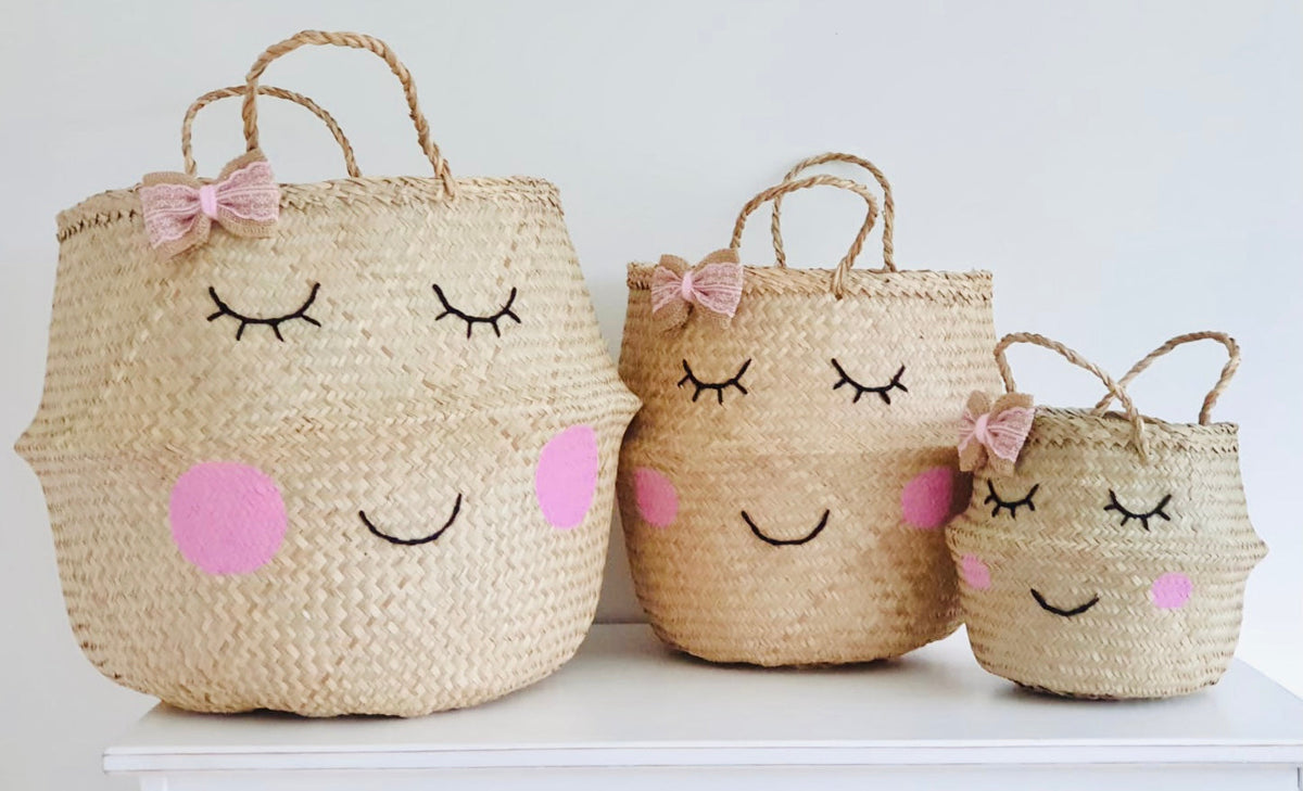 Handwoven seagrass storage basket with smiling face and bow, view 2