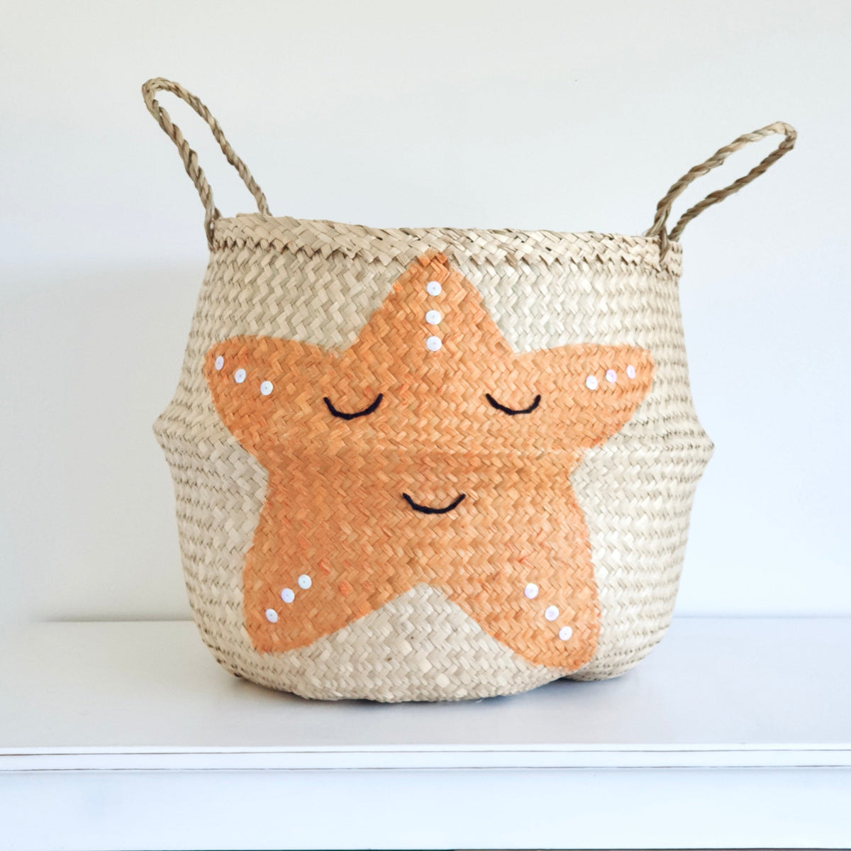 Handwoven seagrass storage basket with orange starfish design