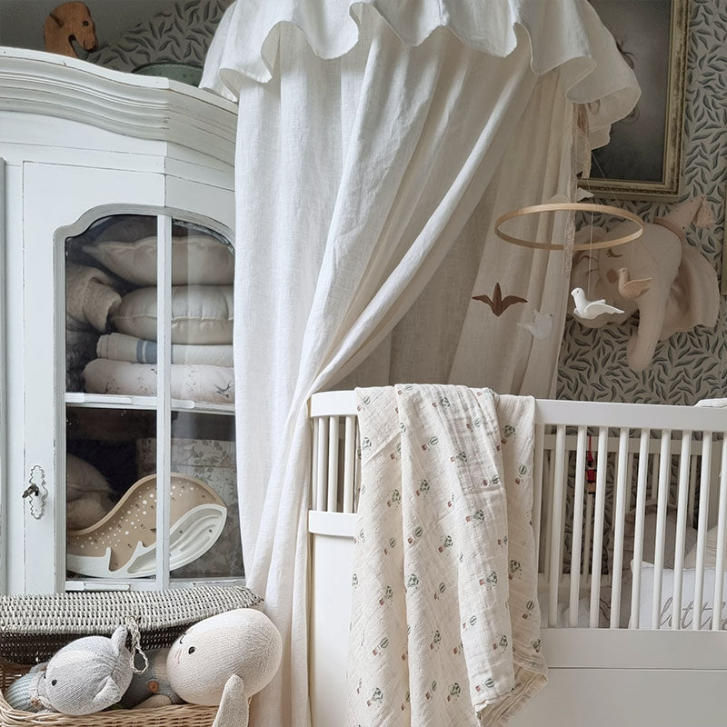 Large Organic Muslin Swaddle with Hot Air Balloon Hand painted Design Evie Skye London hanging over a baby cot - perfect for newborns