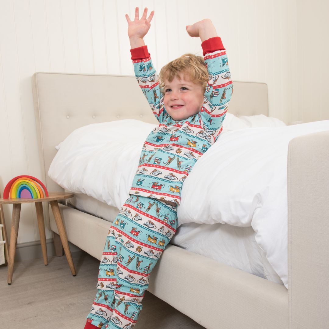 Child in fairisle Roald Dahl x Ducky Zebra pyjamas with mice enjoying their bedtime routine. The red cuffs and trim make them feel festive.