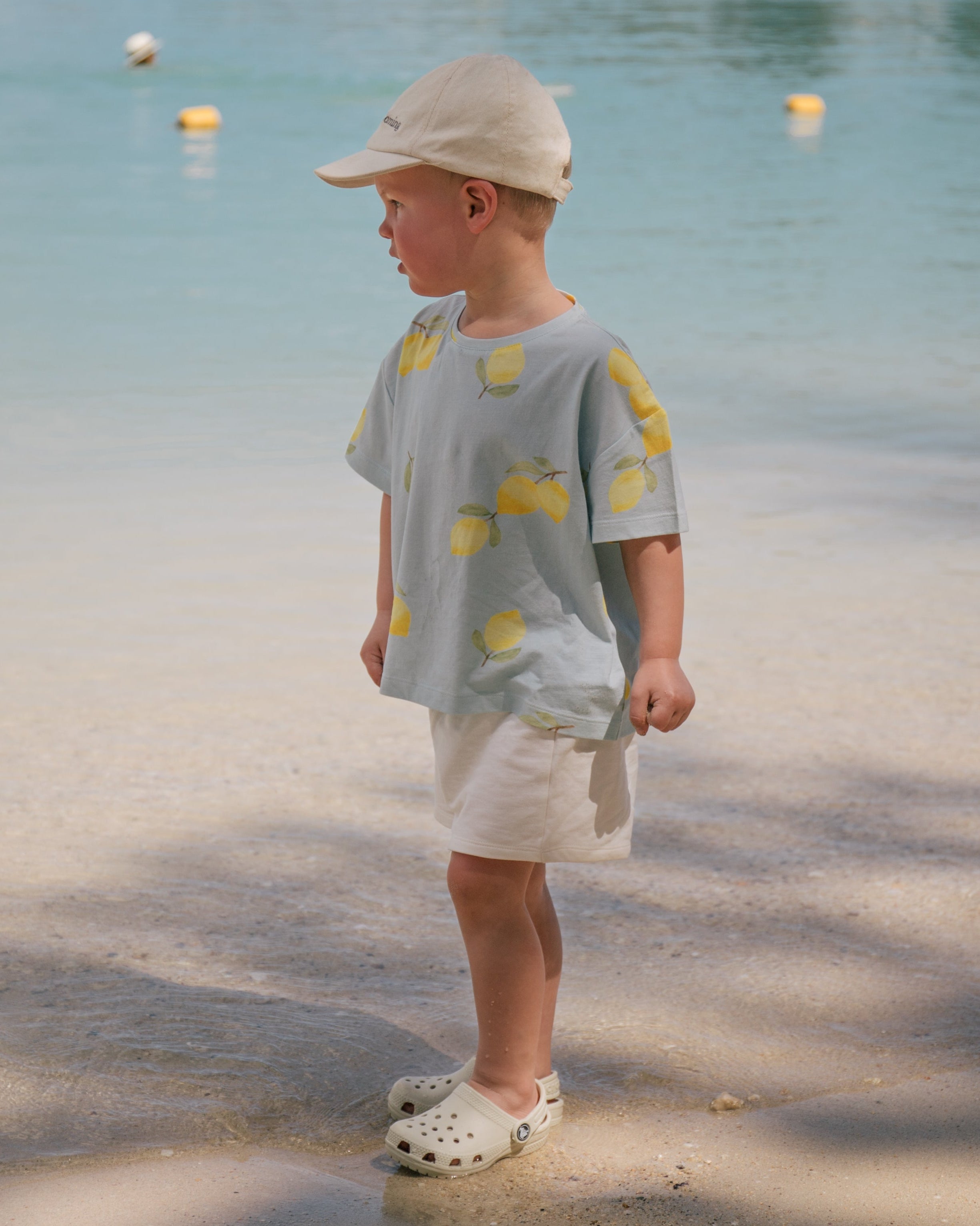 Child wearing a Wildgreen Lemon T-shirt from the Island Life collection. Made from 100% GOTS-certified organic cotton, this unisex kids tee features a zesty lemon print, perfect for eco-conscious families who value sustainable fashion. #OrganicKidsClothing #SustainableKidswear