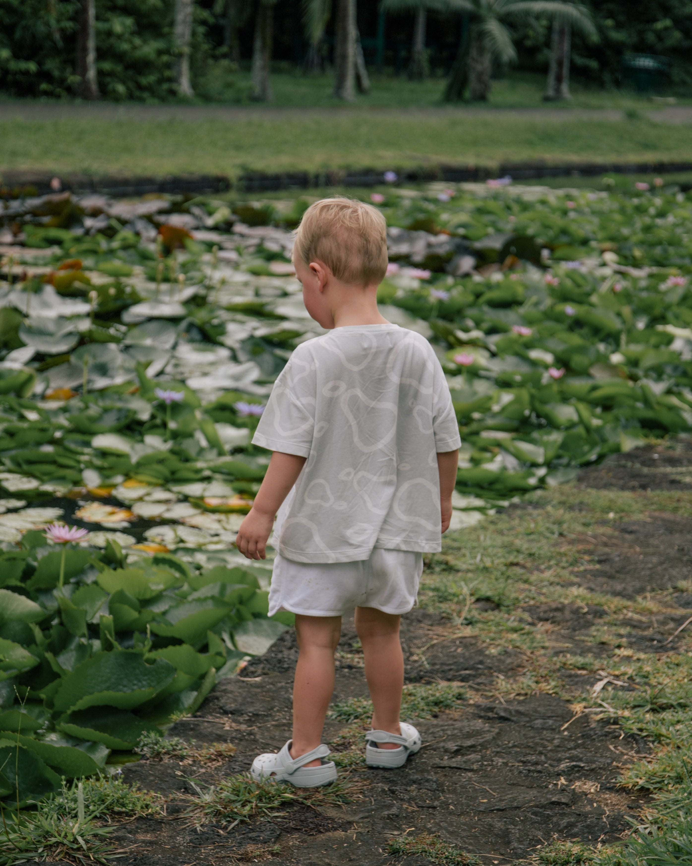 Child wearing Wildgreen’s White Pear T-shirt from the Island Life collection. Made from 100% GOTS-certified organic cotton, this gender-neutral kids tee features a soft apricot-hued print, perfect for eco-conscious families seeking sustainable and stylish clothing. #OrganicKidswear #SustainableFashion