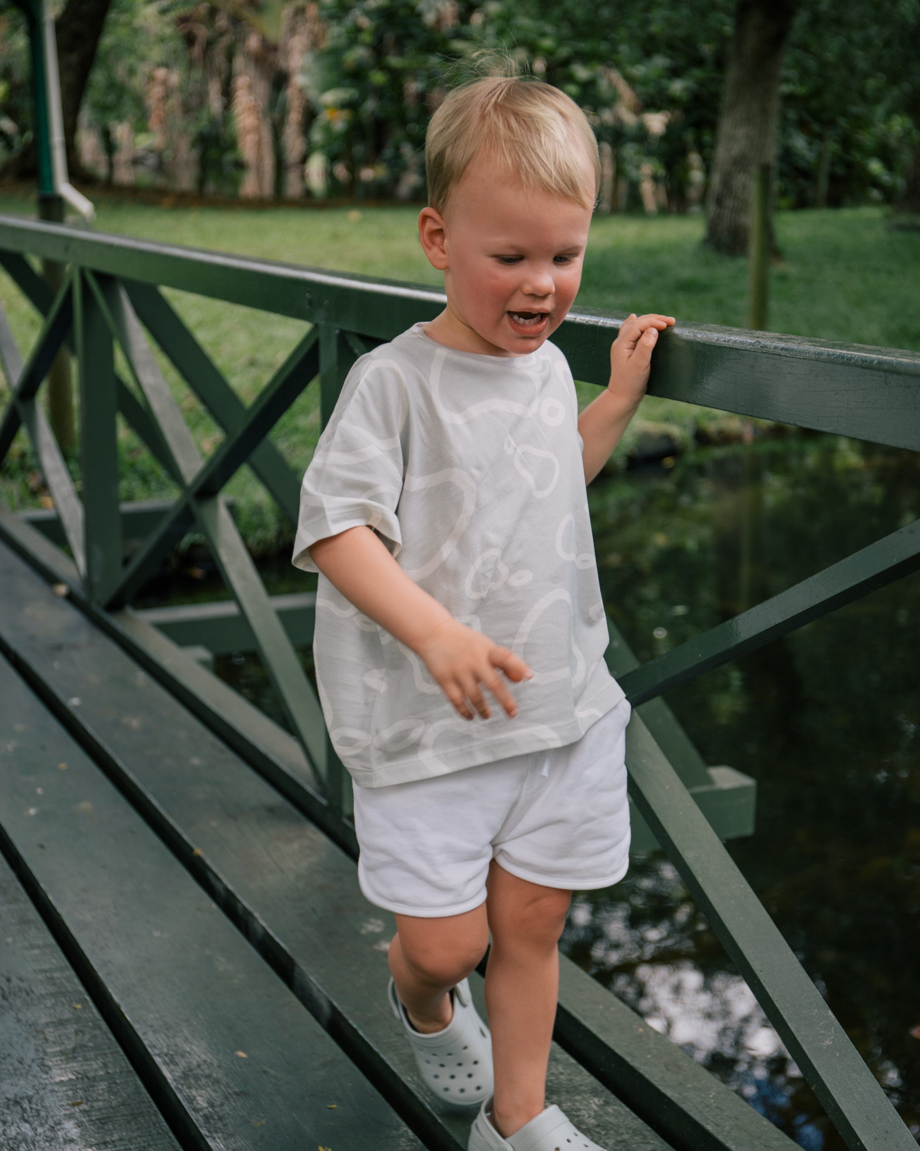 Toddler wearing Wildgreen’s White Pear T-shirt from the Island Life collection. Made from 100% GOTS-certified organic cotton, this unisex kids tee features a soft apricot-hued print, perfect for eco-conscious families seeking sustainable and stylish clothing. #OrganicKidswear #SustainableFashion