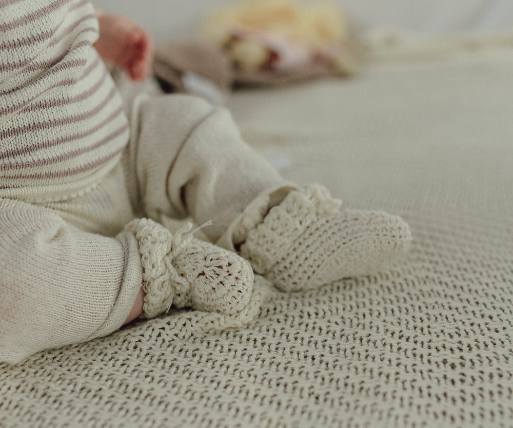 image shows a baby wearing cream organic Cotton tie booties