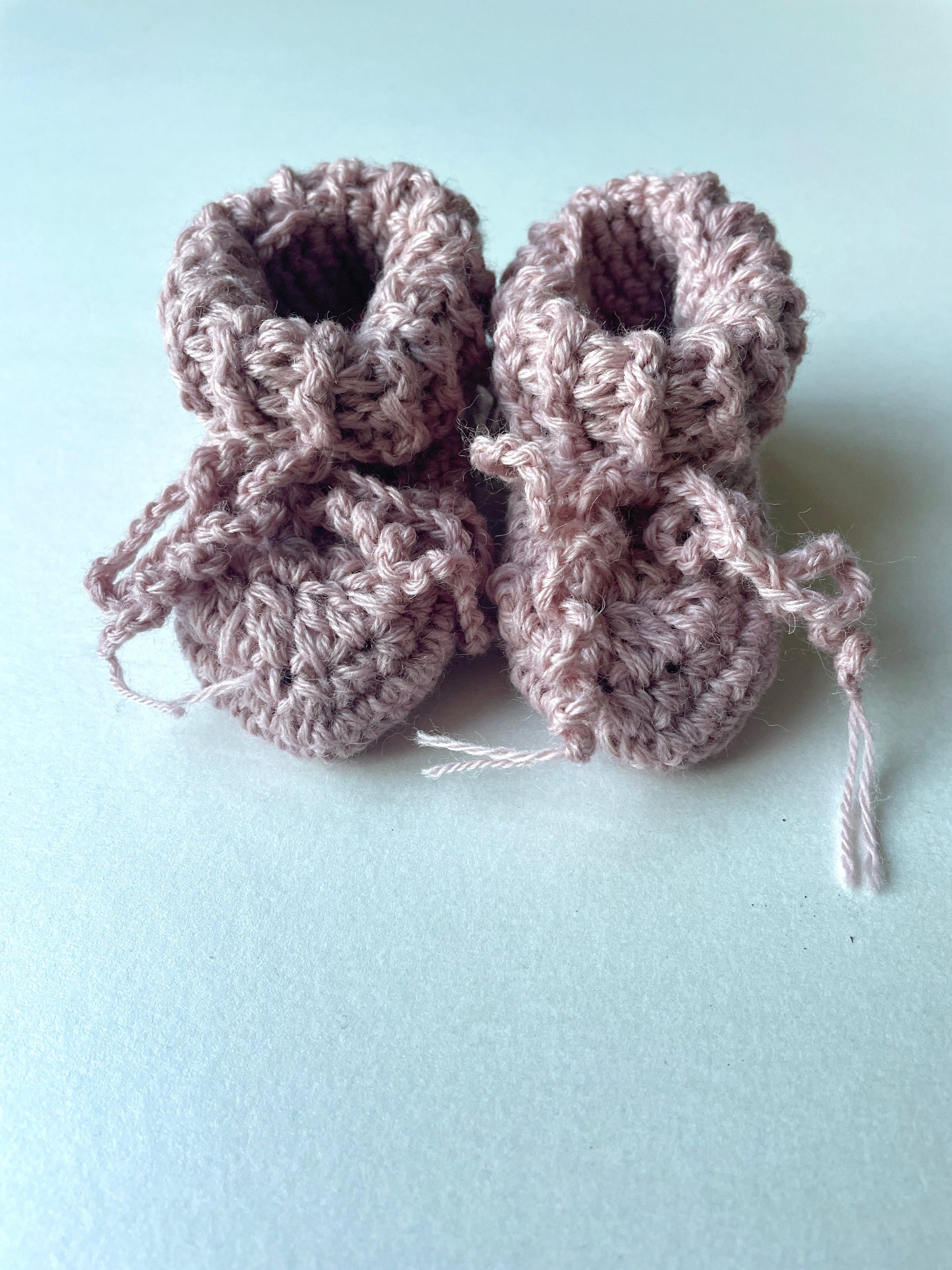 image shows chalky pink organic wool baby booties