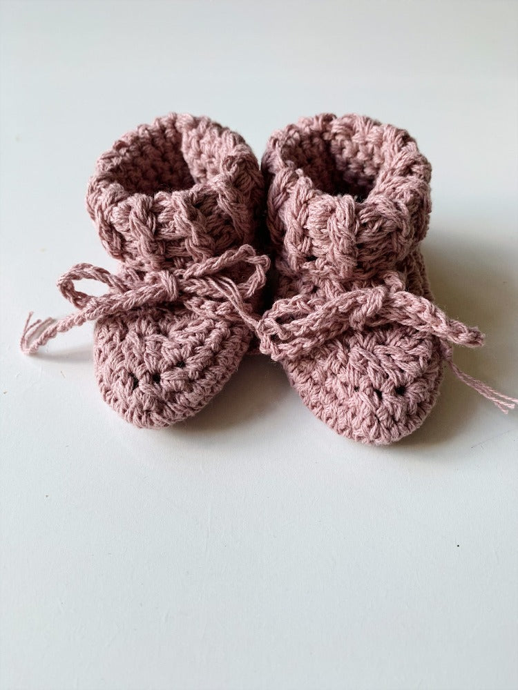 Image shows a pair of pink crocheted booties
