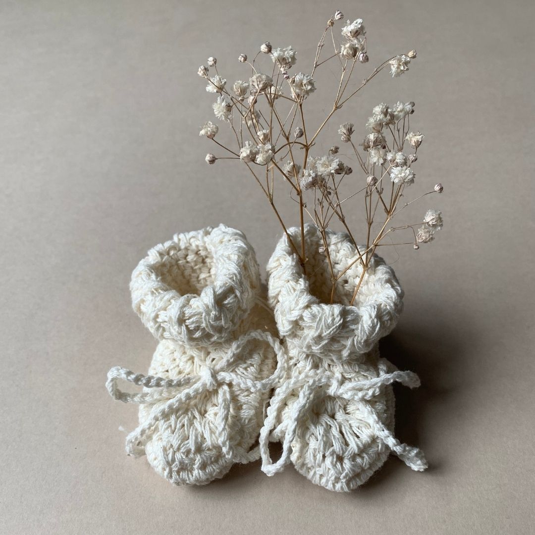 image shows a pair of organic cotton cream baby booties wit tie.