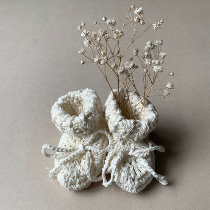 image shows a pair of organic cotton cream baby booties wit tie.