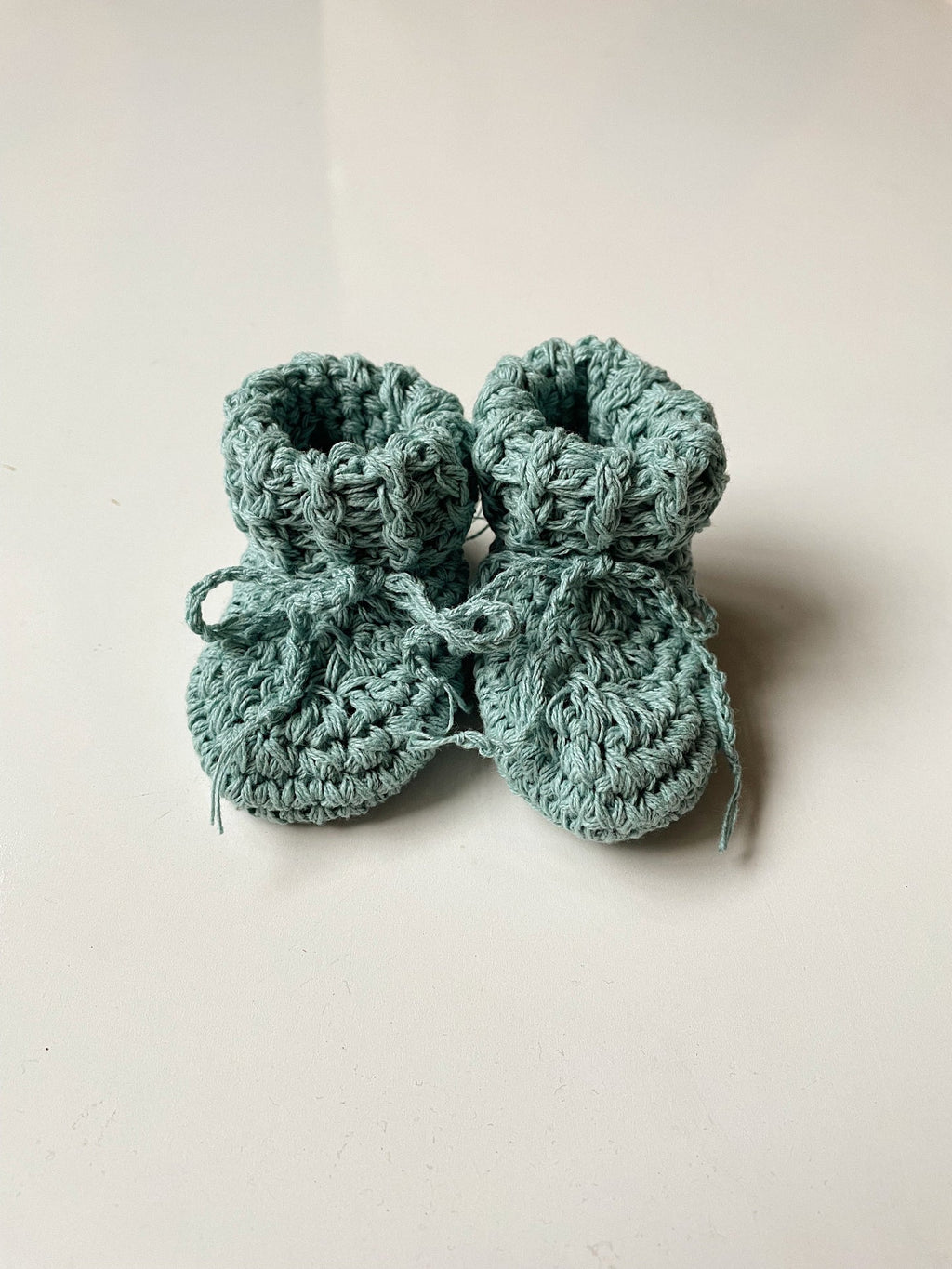 Image shows a pair of duck egg coloured organic cotton baby booties