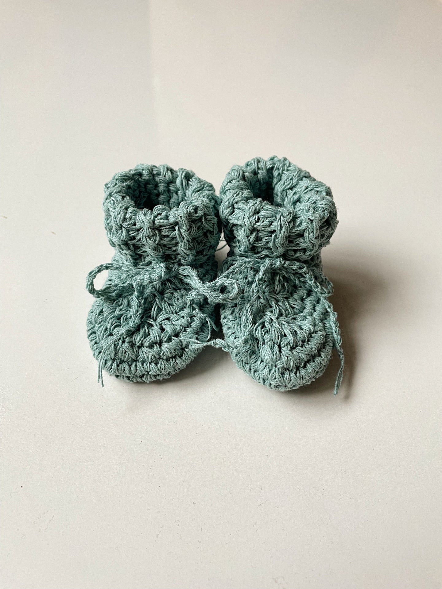 Image shows a pair of duck egg coloured organic cotton baby booties