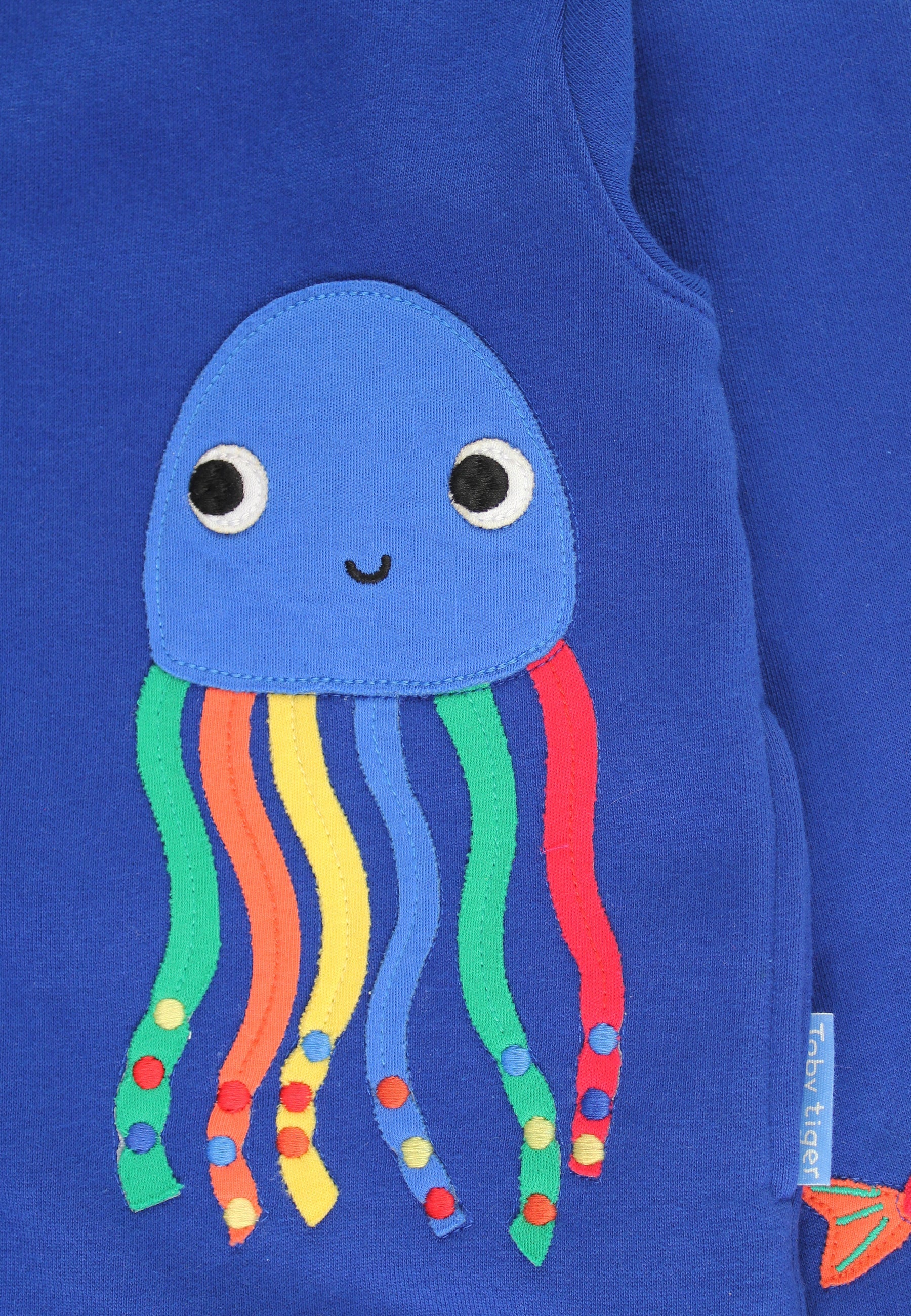 Blue sweater with a colorful jellyfish applique on a blue background