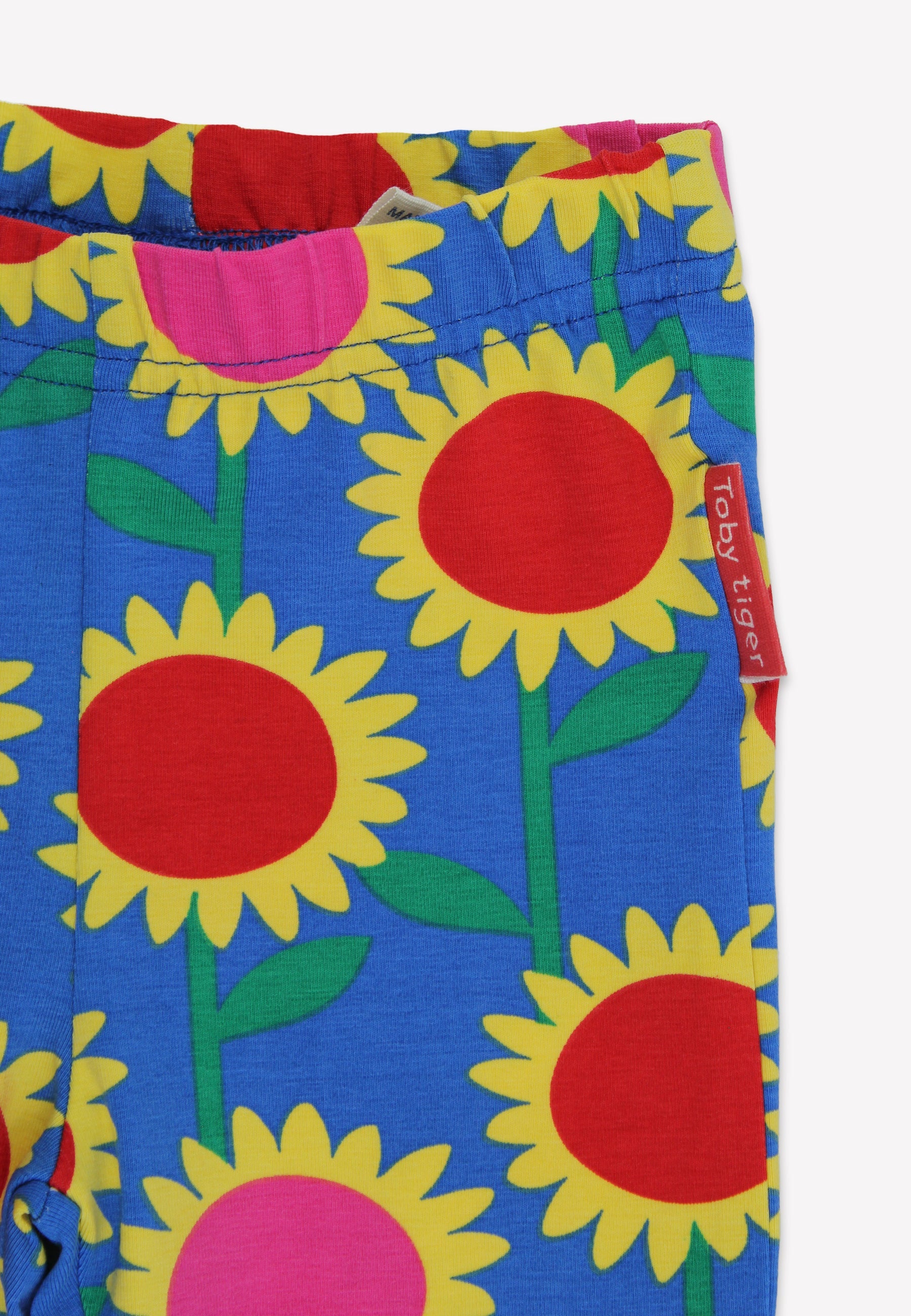 Colorful sunflower patterned fabric with a visible brand tag on a white background