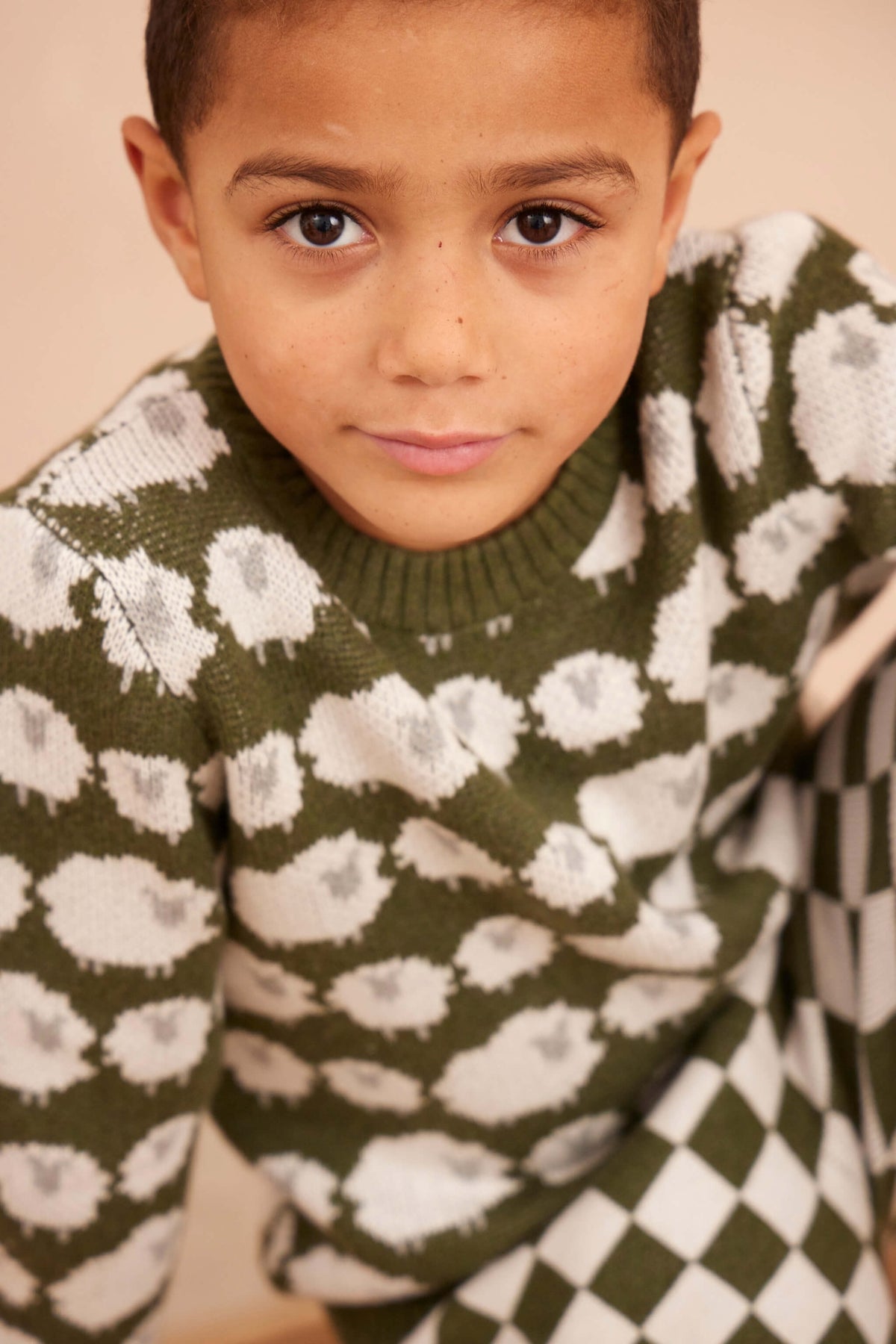 Boy wearing the Flock of Sheep Jumper in avocado green