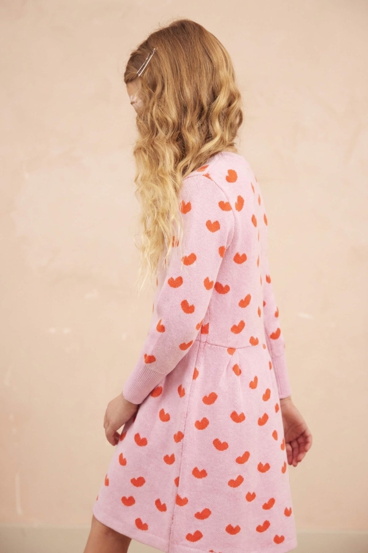 Side view of a girl in the Love Hearts Dress in bubble gum pink