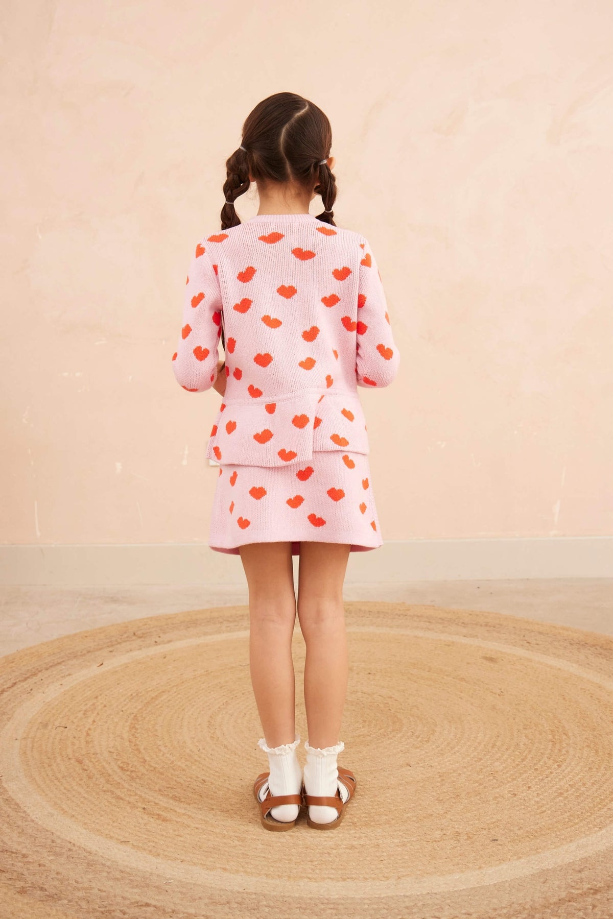 Girl wearing the Love Hearts Peplum Cardigan with the matching skirt in bubble gum pink