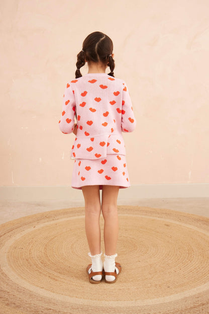 Girl wearing the Love Hearts Peplum Cardigan with the matching skirt in bubble gum pink