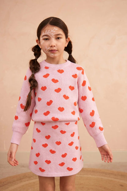 Girl standing against a plaster wall in the Love Hearts set in bubble gum pink
