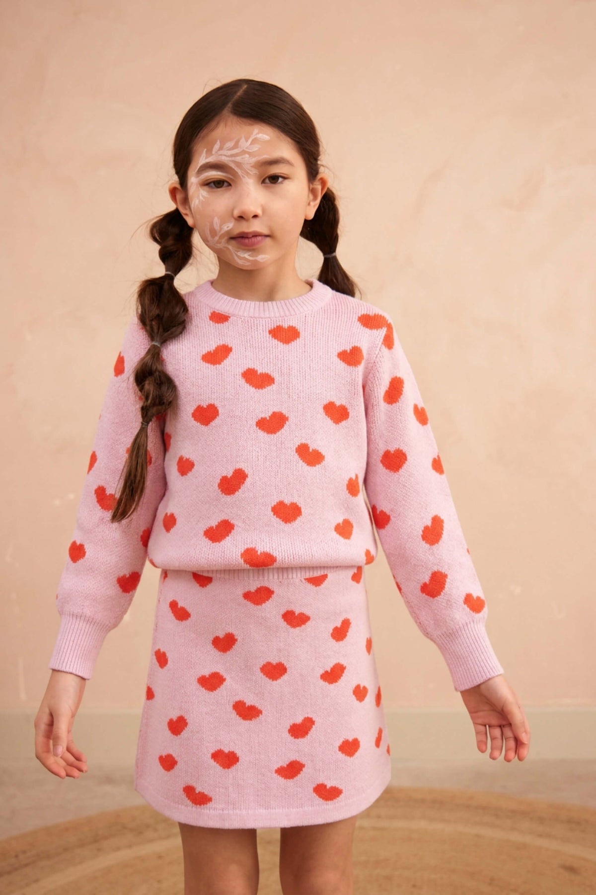 Girl standing against a plaster wall in the Love Hearts set in bubble gum pink