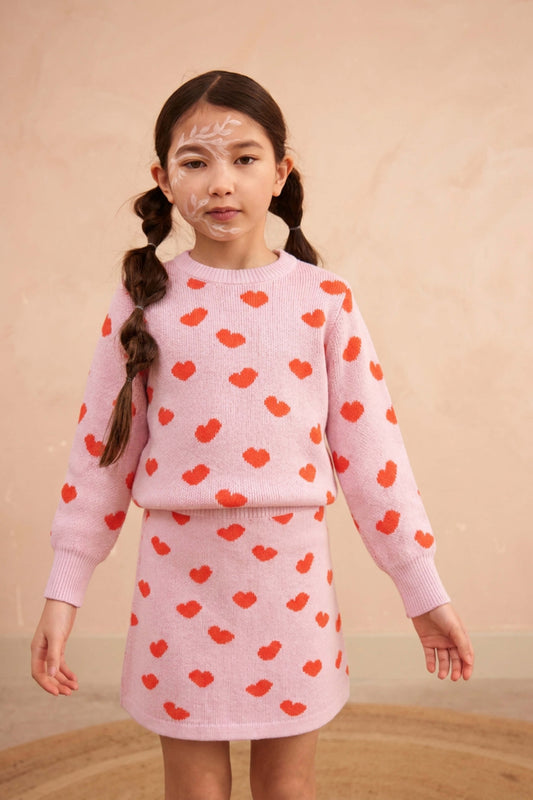 Girl standing against a plaster wall in the Love Hearts set in bubble gum pink