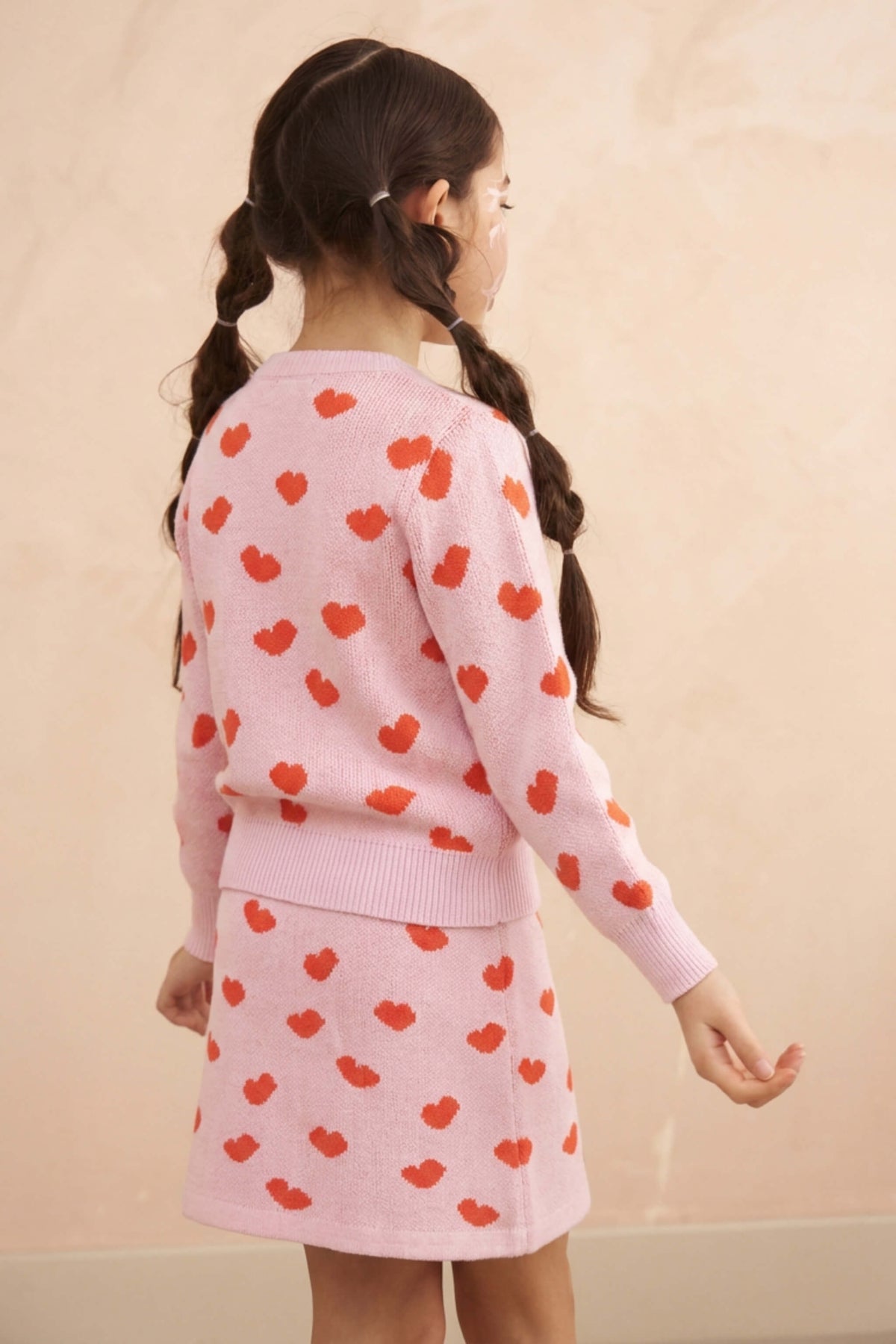 Girl wearing the Love Hearts skirt and jumper set in bubble gum pink