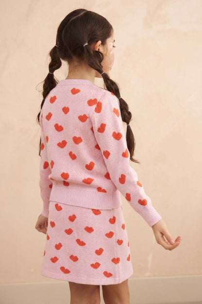 Girl wearing the Love Hearts skirt and jumper set in bubble gum pink