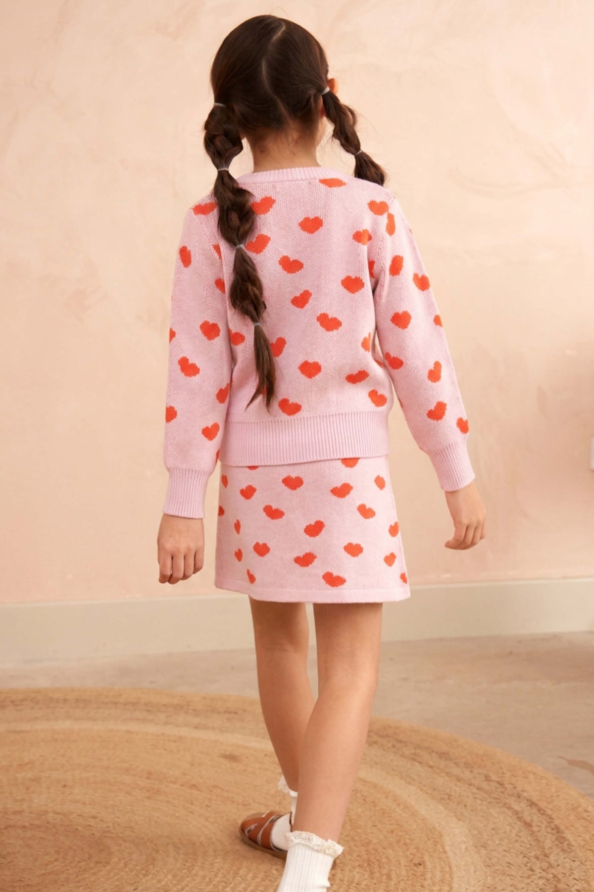 Side view of a girl in the Love Hearts skirt in bubble gum pink