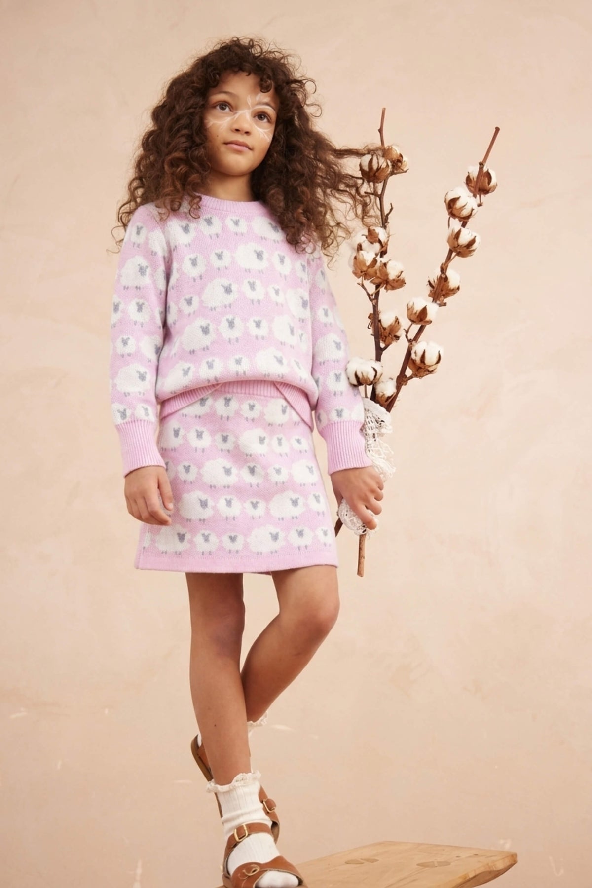 Girl standing against a plaster wall in the Little Bo Peep set in bubble gum pink