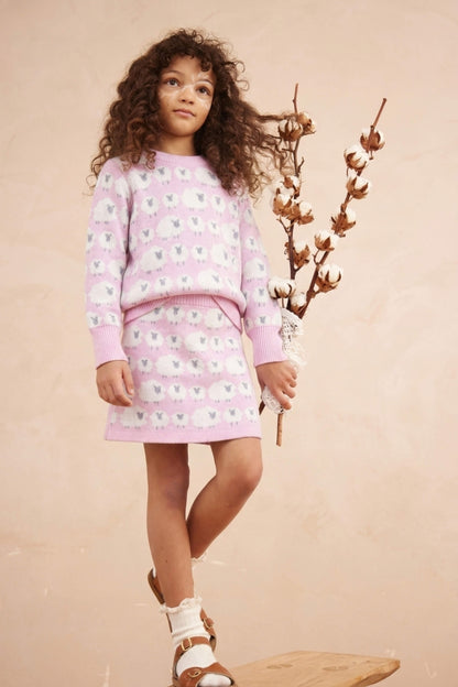 Girl standing against a plaster wall in the Little Bo Peep set in bubble gum pink