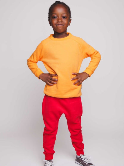 A boy wearing an orange jumper and red joggers - Hues Clothing