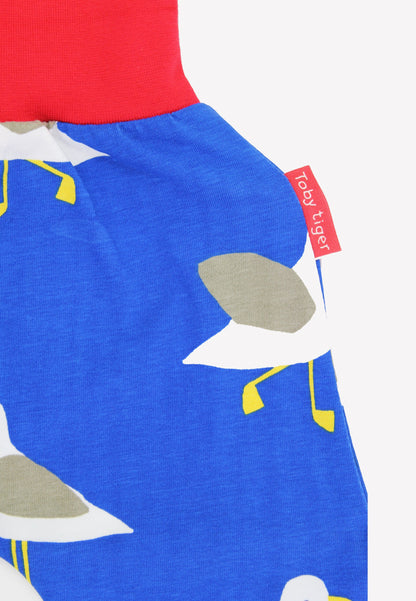 Close-up of a blue garment with bird pattern and red label, featuring the brand 'Toby Tiger'.
