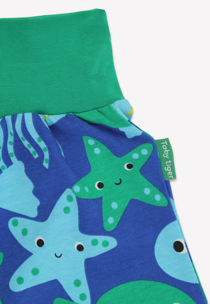 Children's pants with starfish pattern and green waistband on a white background