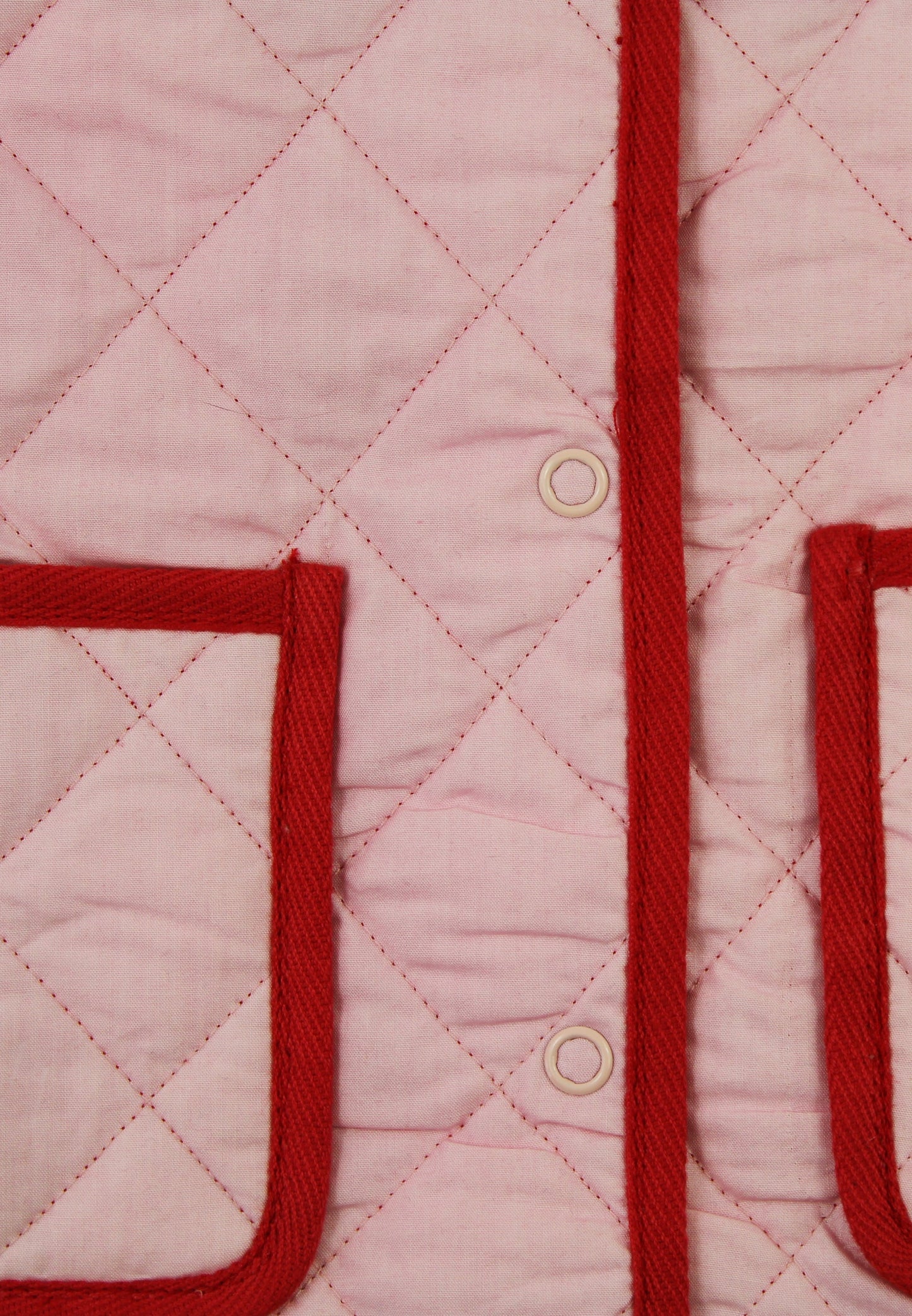 Close-up of a pink quilted jacket with red trim and buttons.