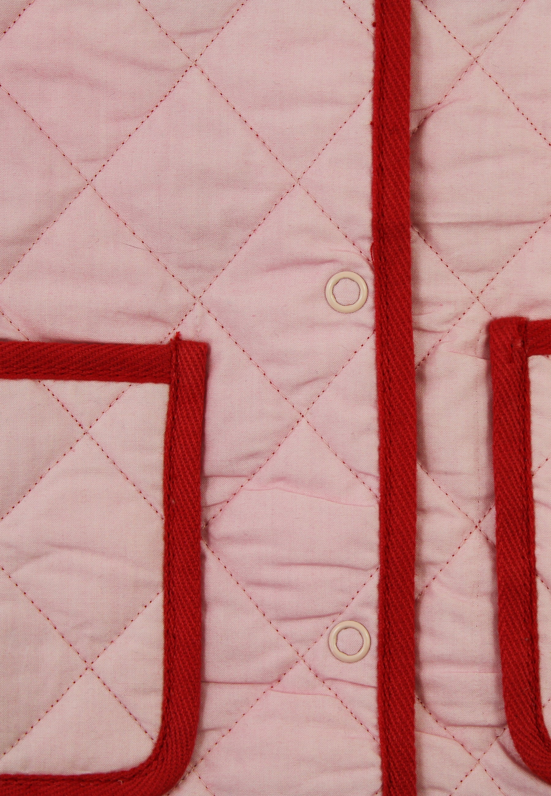 Close-up of a pink quilted jacket with red trim and buttons.