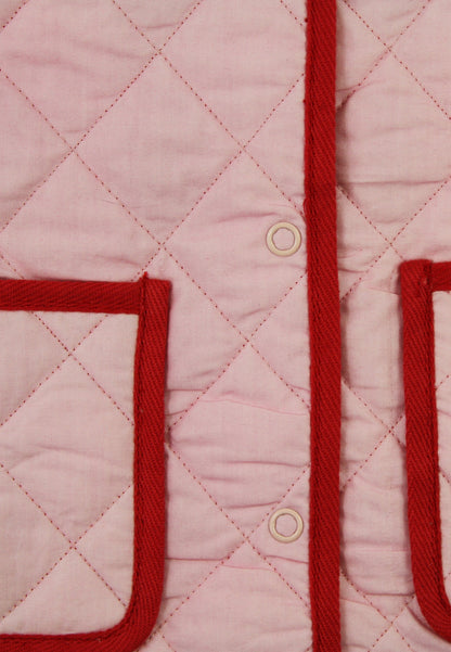 Close-up of a pink quilted jacket with red trim and buttons.